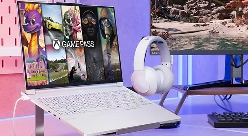 Das Notebook aufgeklappt  und am Bildschirm steht Game Pass. Weiße Kopfhörer hängen daneben