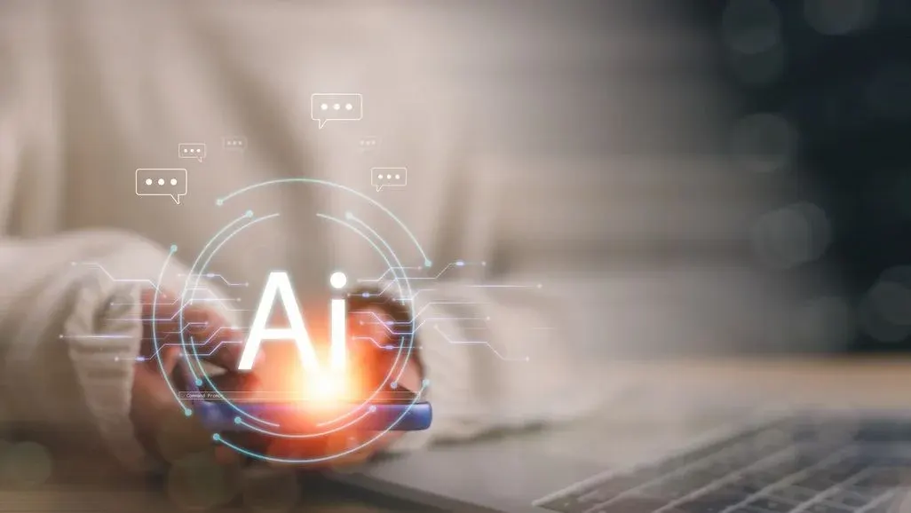 Hand hält leuchtende holografische AI-Sphäre mit Sprechblasen und Schaltkreisen, symbolisiert künstliche Intelligenz und digitale Kommunikation.