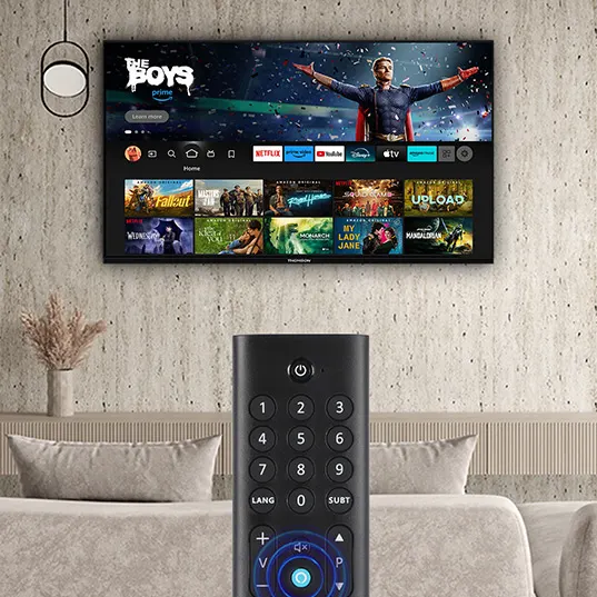 Ein Fernseher zeigt eine Menüauswahl mit einer schwarzen Fernbedienung davor, die auf einem beigen Sofa platziert ist.