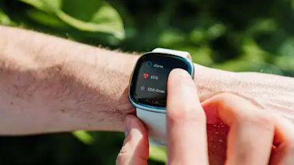 Person bedient eine Smartwatch mit weissem Armband im Freien