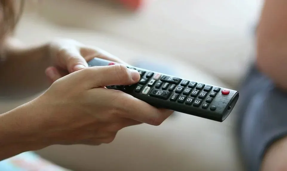 Nahaufnahme einer Hand die eine Fernbedienung nutzt.