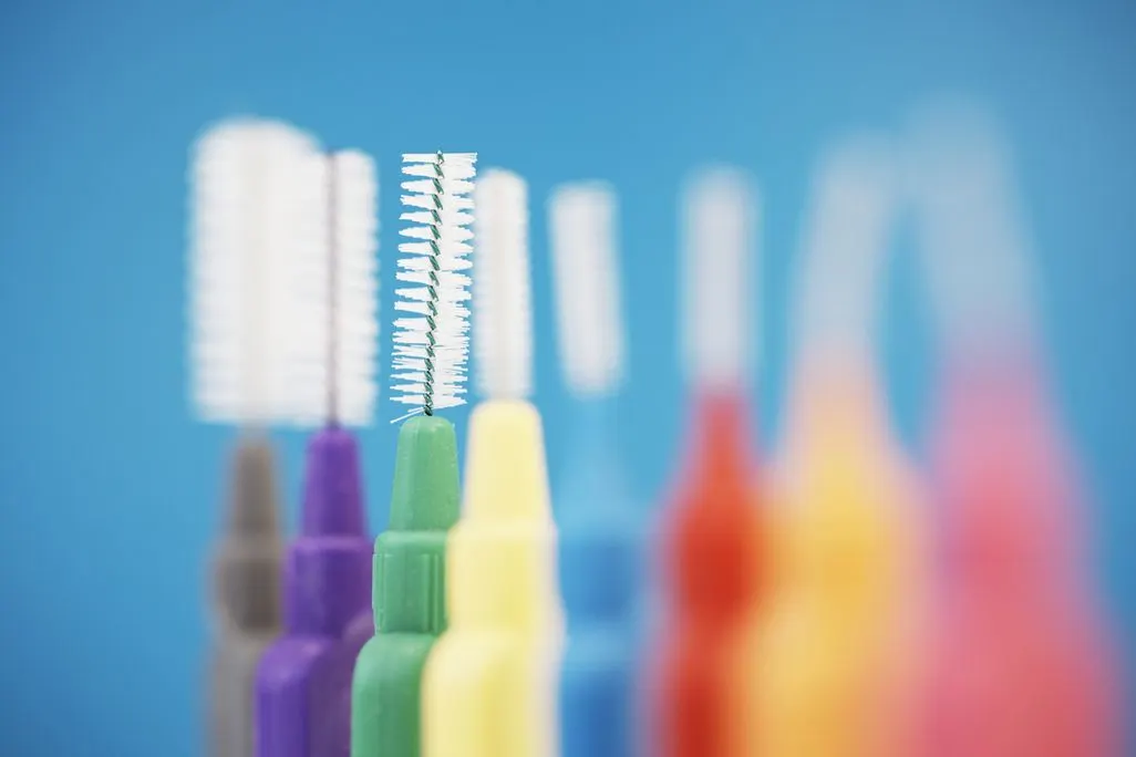 Mehrere bunte Interdentalbuersten vor blauem Hintergrund