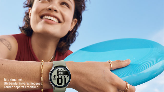 Eine Frau lächelt mit einer blauen Frisbeescheibe in der Hand. Sie trägt eine Smartwatch am Handgelenk, und im Hintergrund ist ein blauer Himmel.