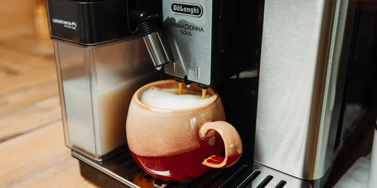Nahaufnahme des Kaffeeauslass der De Longhi PrimaDonnaSoul mit roter Tasse