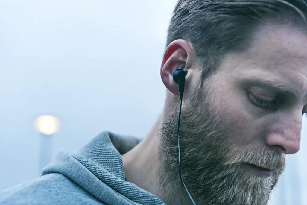 Mann trägt schwarze kabelgebundene In-Ear Kopfhörer.