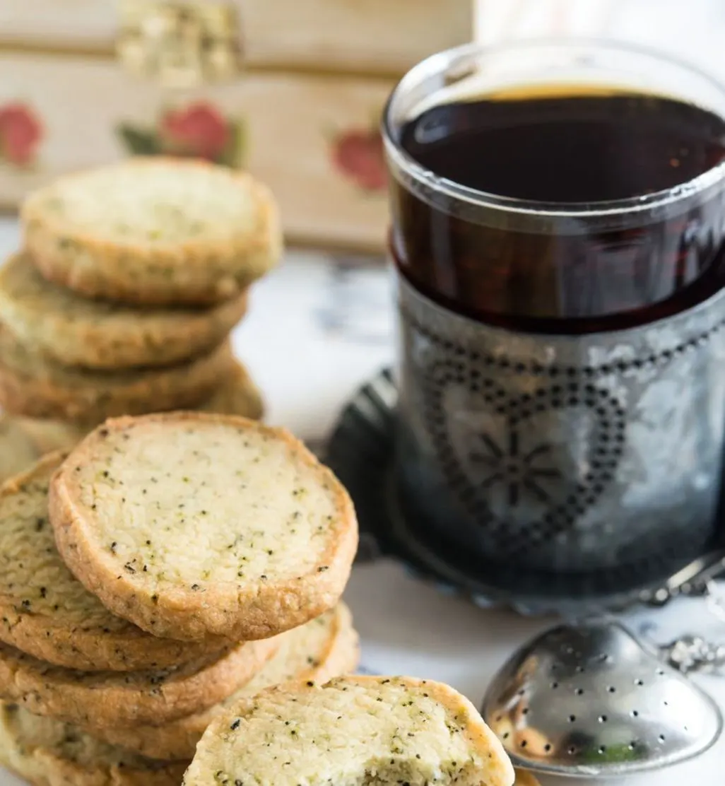 Runde Teeplätzchen gestapelt neben einer Tasse Tee in silbernem Halter.