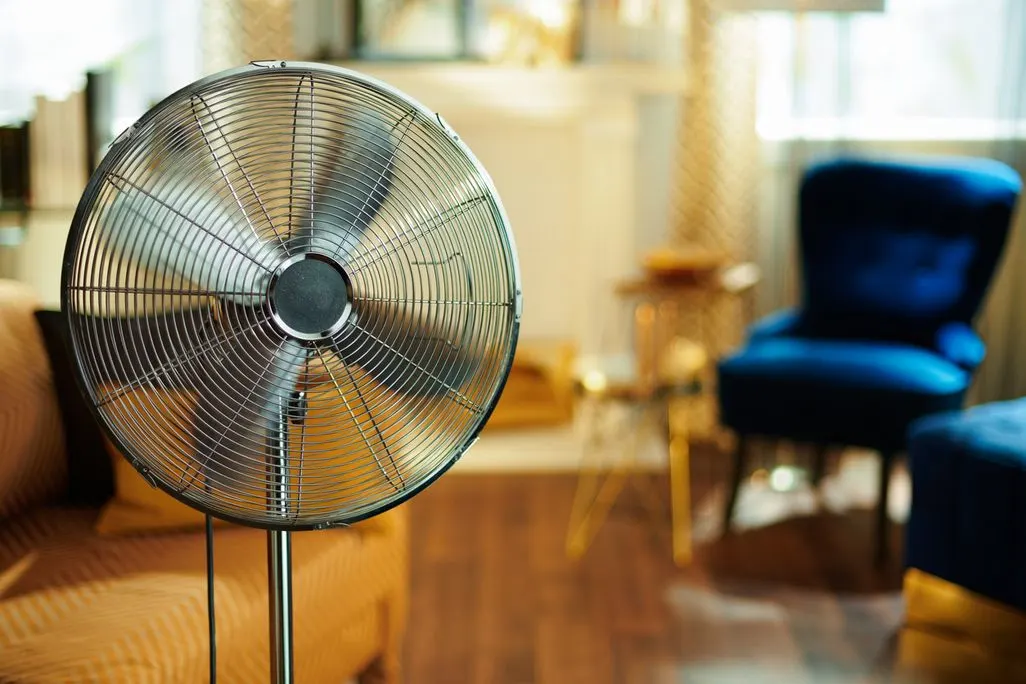 Grosser Standventilator im Wohnzimmer mit Couch und Sessel im Hintergrund