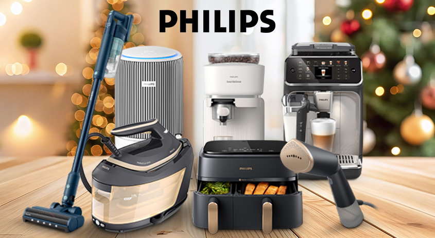 Auf einem Holztisch stehen verschiedene Philips-Haushaltsgeräte vor einem verschwommenen Hintergrund. Zu sehen sind ein Staubsauger, ein Luftreiniger, eine Kaffeemaschine und ein Dampfbügeleisen.