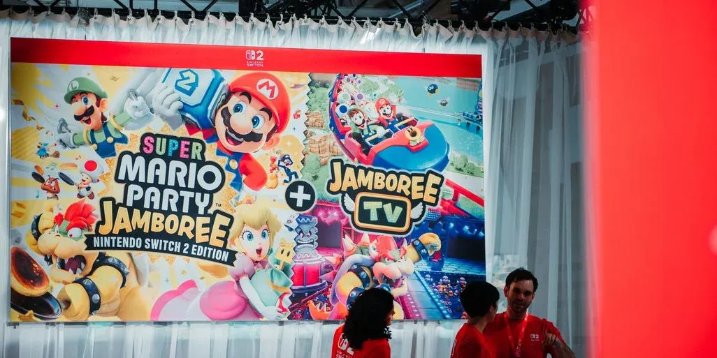 Großes Messebanner für „Super Mario Party Jamboree + Jamboree TV“ (Nintendo Switch 2 Edition), davor stehen mehrere Personen in roten Shirts.