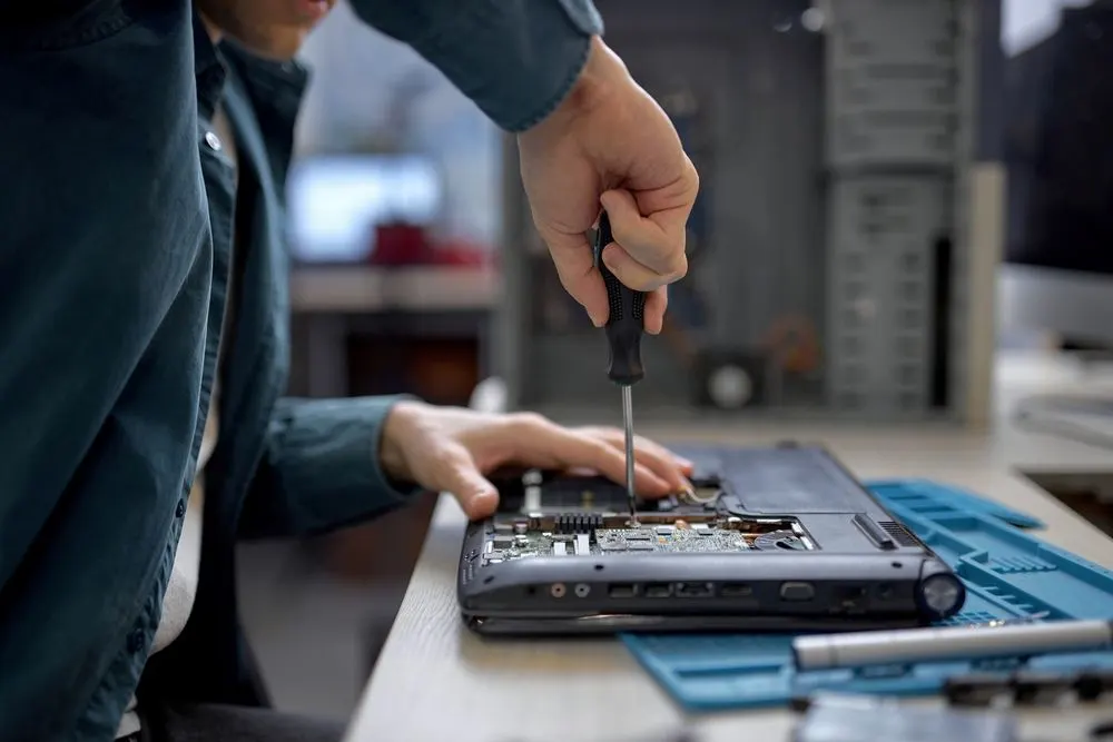Techniker repariert Laptop mit Schraubendreher  - Komponenten sind sichtbar.