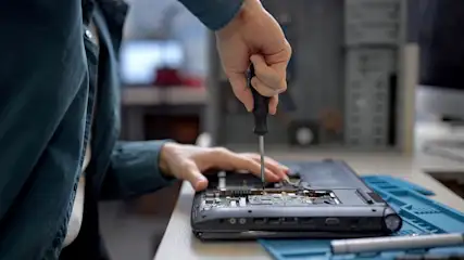 Techniker repariert Laptop mit Schraubendreher - Komponenten sind sichtbar.