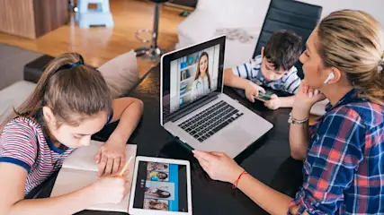 Familie mit Kindern nutzt Laptop und Tablet für Videocall mit Ärztin
