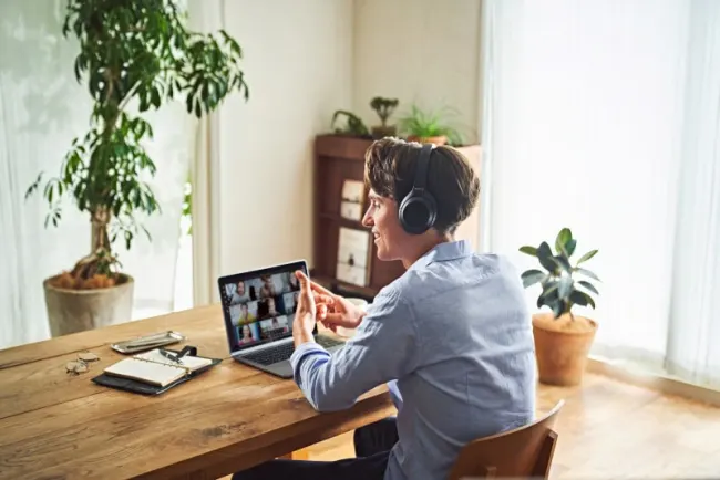 Mann mit Kopfhörer hat eine Videokonferenz am Notebook