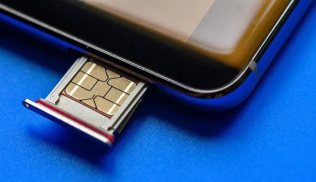Eine SIM-Karte steckt in einem Smartphone auf einem blauen Hintergrund