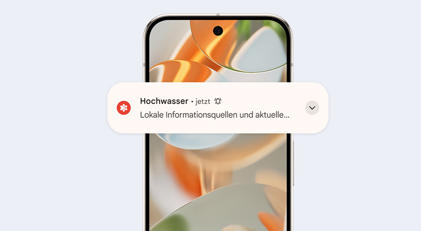 Ein Smartphone zeigt eine Benachrichtigung mit "Hochwasser • jetzt" und lokalen Informationsquellen auf hellem Hintergrund.