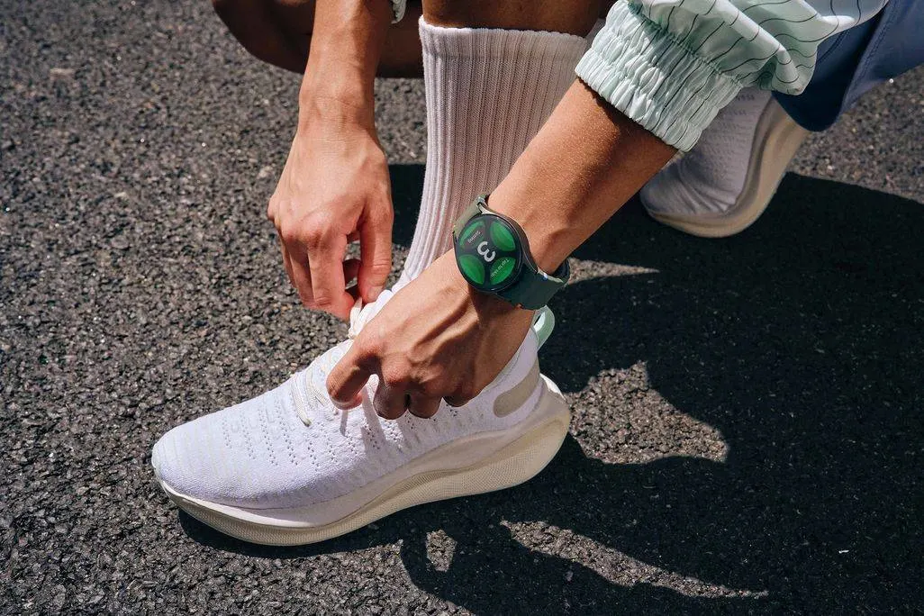 Person bindet auf der Strasse einen Sportschuh und trägt eine grüne Smartwatch