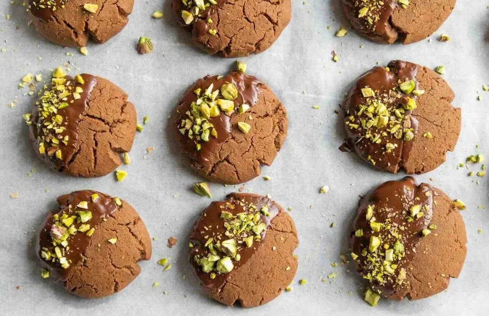 Schoko-Kekse mit Pistazien und Schokoglasur auf einem Backblech.
