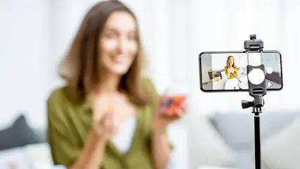 Eine Frau filmt sich selbst mit einem Smartphone und präsentiert einen bunten Gegenstand.