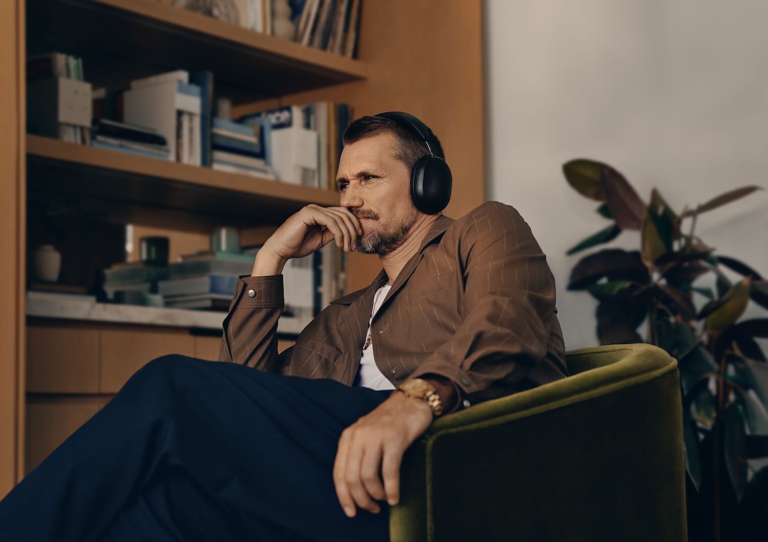 Ein Mann mit konzentriertem Blick sitzt in einem Sessel im Heimkino und trägt Kopfhörer.