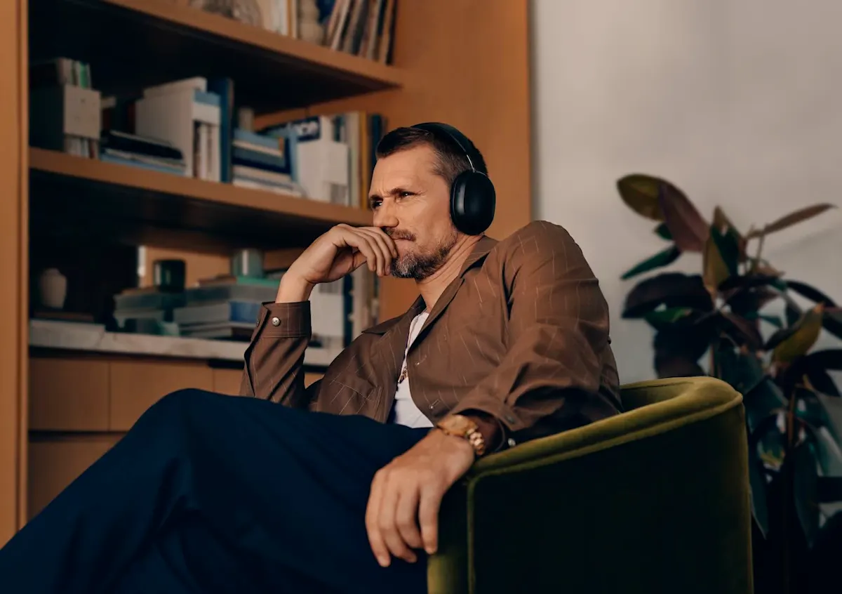 Ein Mann mit konzentriertem Blick sitzt in einem Sessel im Heimkino und trägt Kopfh