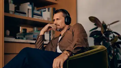 Ein Mann mit konzentriertem Blick sitzt in einem Sessel im Heimkino und trägt Kopfhörer.