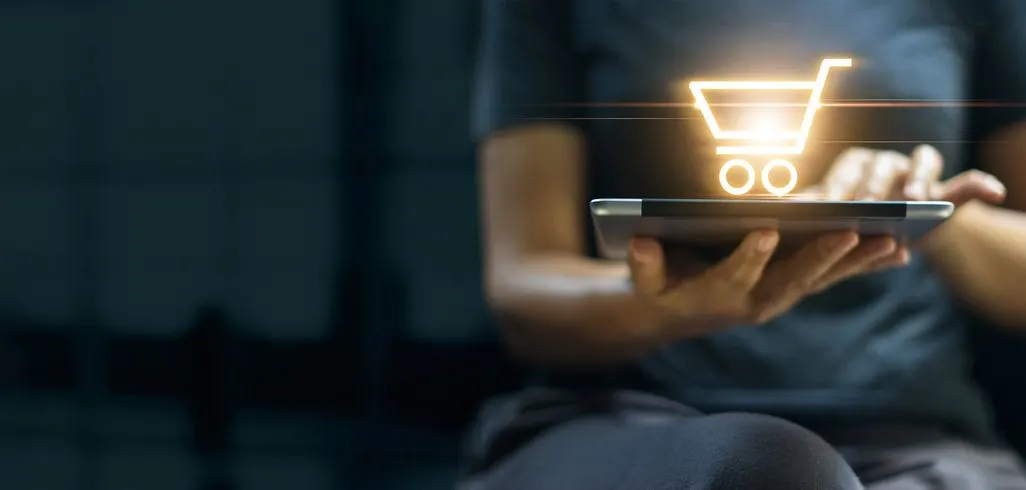 Person bedient ein Tablet mit leuchtendem Einkaufswagensymbol über dem Display.