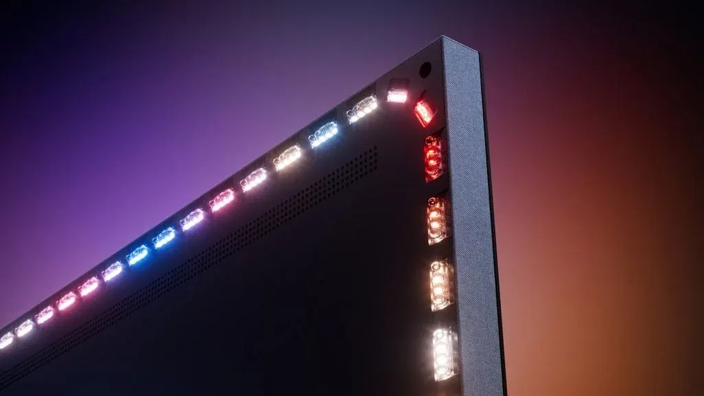 Nahaufnahme der oberen rechten Ecke eines Philips OLED-Fernsehers, die das Ambilight-LED-System von hinten zeigt. Entlang der Oberkante sind mehrere kleine LED-Module in verschiedenen Farben – Weiß, Pink und Blau – sichtbar, während an der rechten Seite des Rahmens LEDs in Rot, Orange und Weiß leuchten. Der Hintergrund zeigt einen dunklen Farbverlauf von Lila zu Orange-Rot.