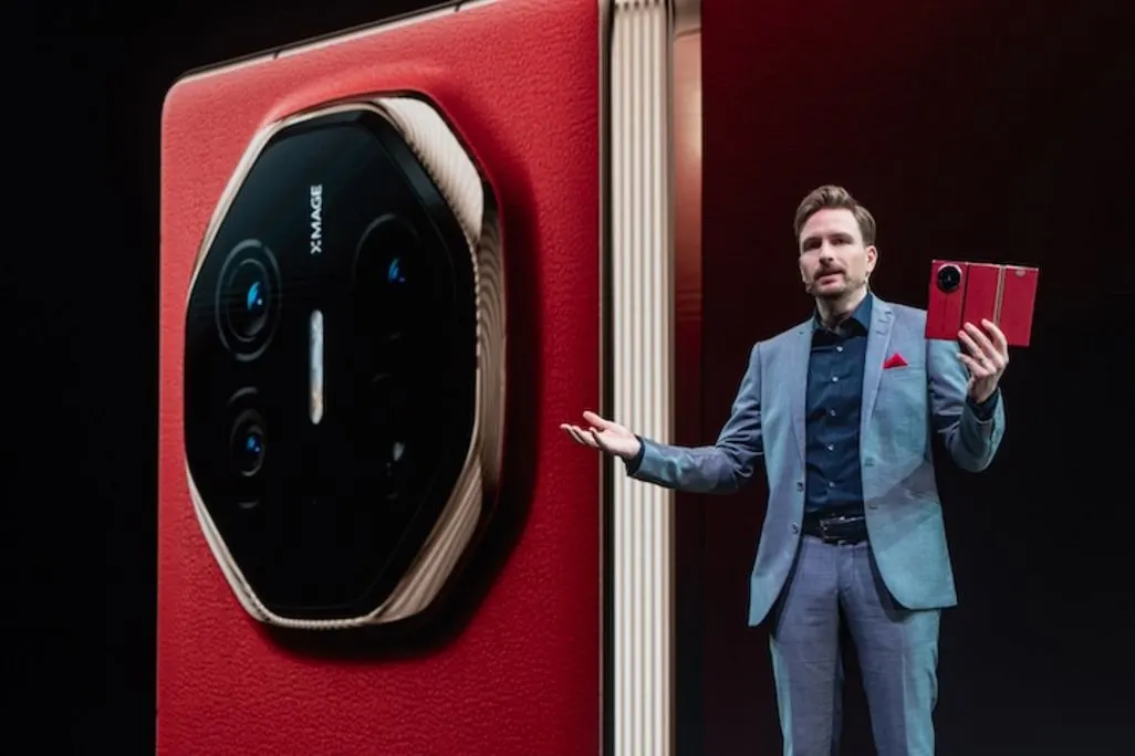 Mann praesentiert ein rotes Huawei Falt-Smartphone vor grosser Leinwand