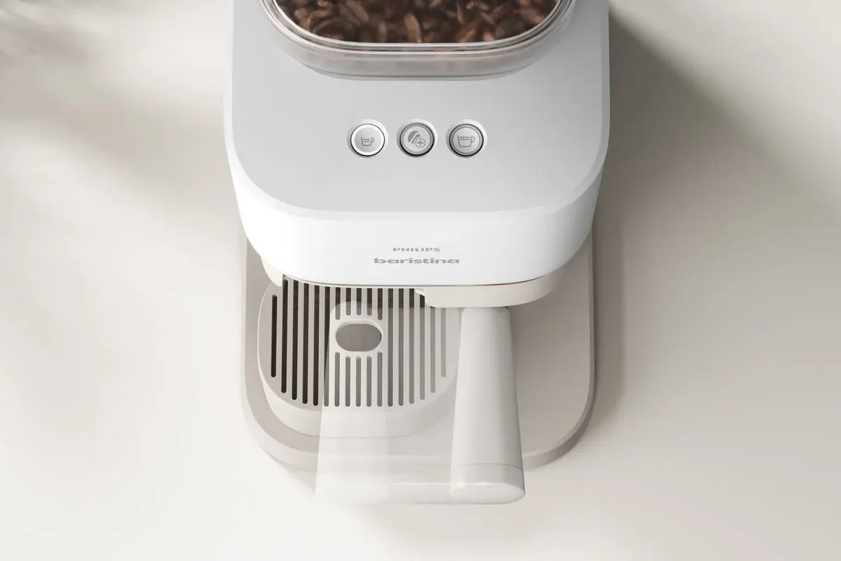 Philips Baristina Kaffee­maschine von oben, ein Becher wird unter dem Auslauf positioniert, darüber Bohnenbehälter und drei Bedientasten.