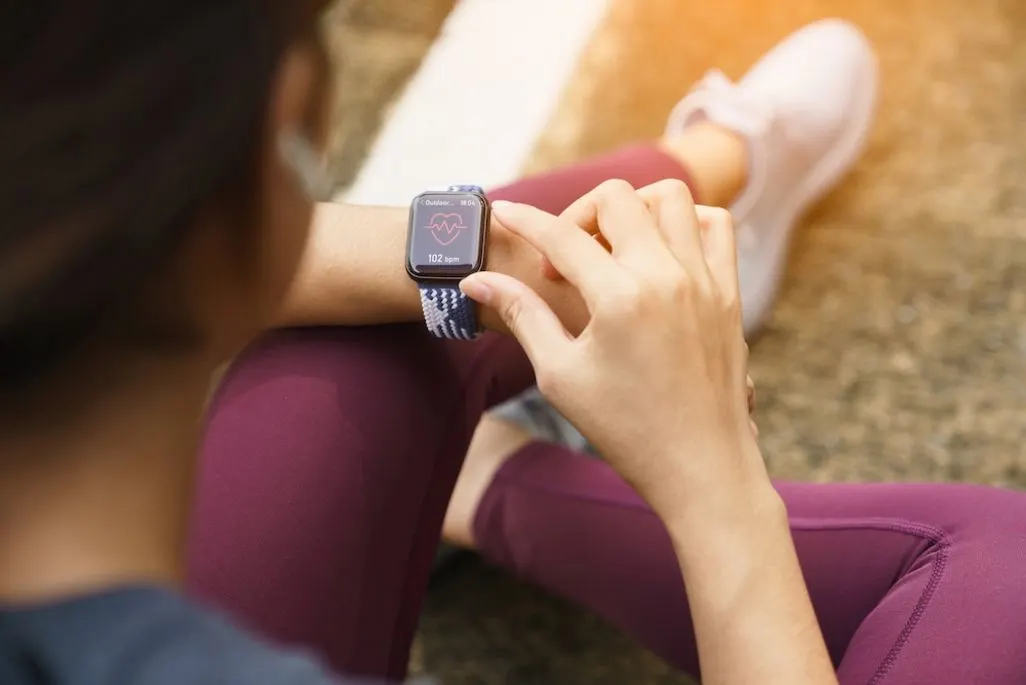 Frau in Sportkleidung betrachtet die Herzfrequenz auf einer Smartwatch.
