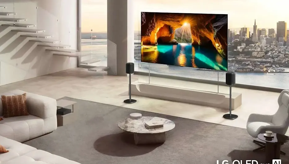 Weitläufiges, helles Wohnzimmer mit freistehendem, großem LG OLED-Fernseher auf schlankem Ständer, der eine leuchtende Meeresgrotte zeigt; zwei schlanke Lautsprecher auf Ständern; helle Polstermöbel, runder Marmorcouchtisch und ein moderner Sessel; große Glasfenster mit Blick auf eine Stadtsilhouette und eine Treppe mit Glasgeländer im Hintergrund. Logo „LG OLED evo AI W6“ sichtbar.