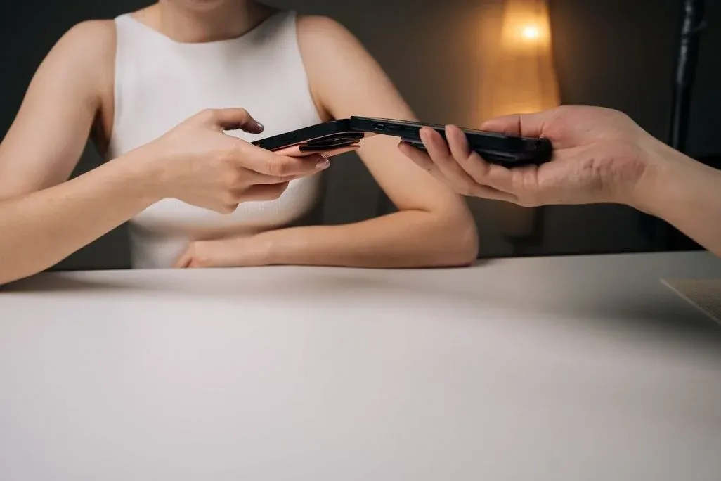 Zwei Personen halten ihre Smartphones aneinander, um per NFC Daten oder kontaktlose Zahlung zu übertragen.