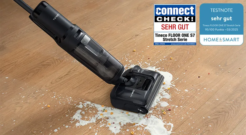 Tineco FLOOR ONE S7 Stretch saugt und wischt Milch und Krümel von einem Holzboden; daneben zwei Testsiegel mit der Bewertung „sehr gut“ von connect und home&smart.