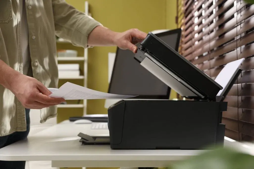 Person legt ein Dokument auf den Flachbettscanner eines Multifunktionsdruckers zum Scannen oder Kopieren.