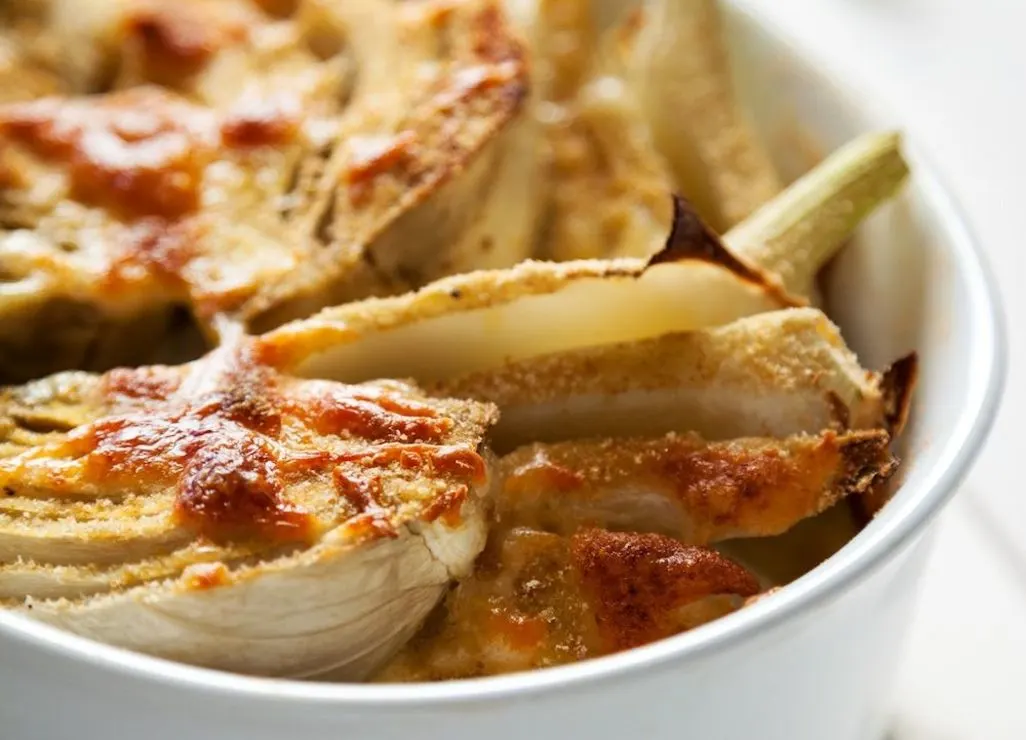 Überbackener Fenchel mit Käse und Bröseln in einer weißen Auflaufform