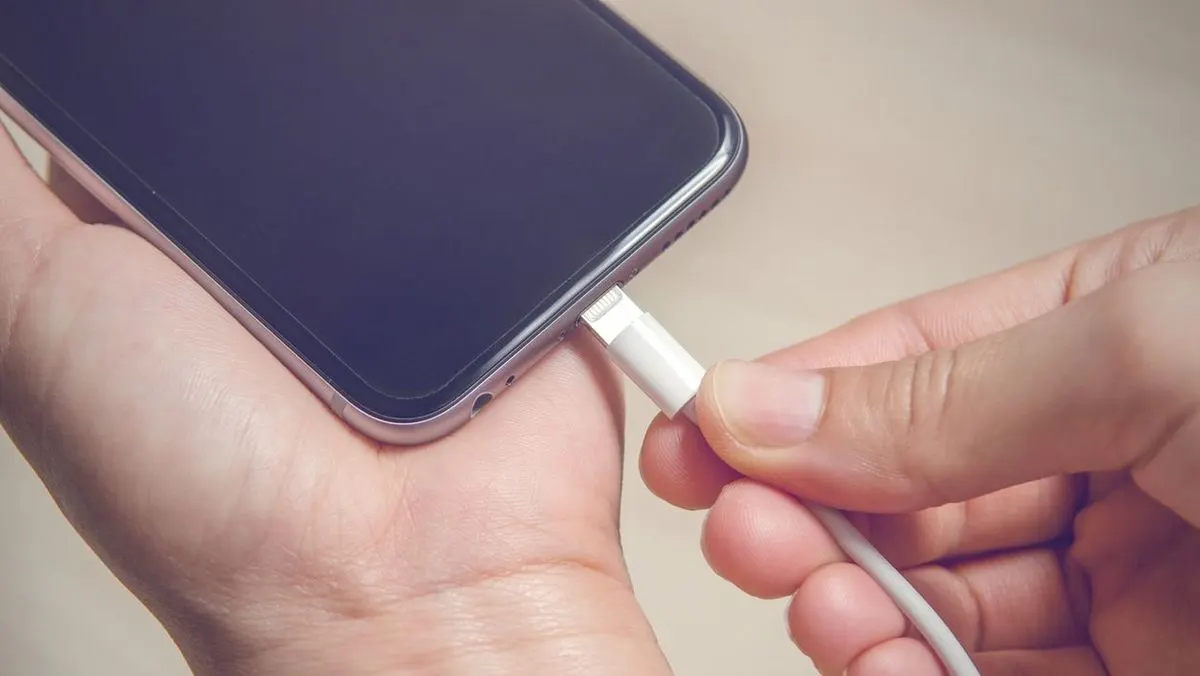 Person steckt Ladekabel in ein Smartphone