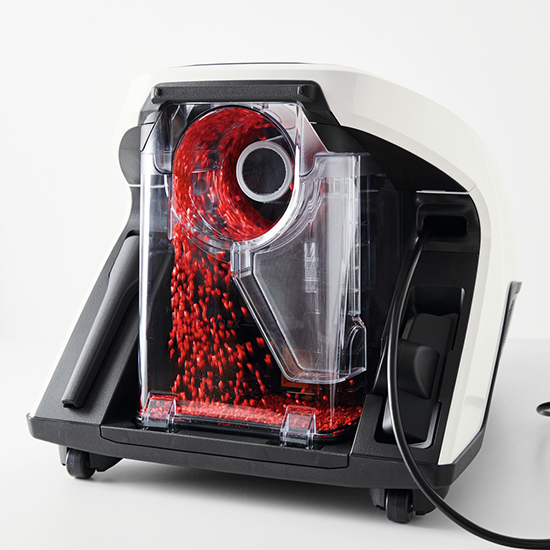 Eine Maschine mit einem transparenten Behälter, der rote Kügelchen enthält, die nach unten fließen. Das Gehäuse ist schwarz und weiß.