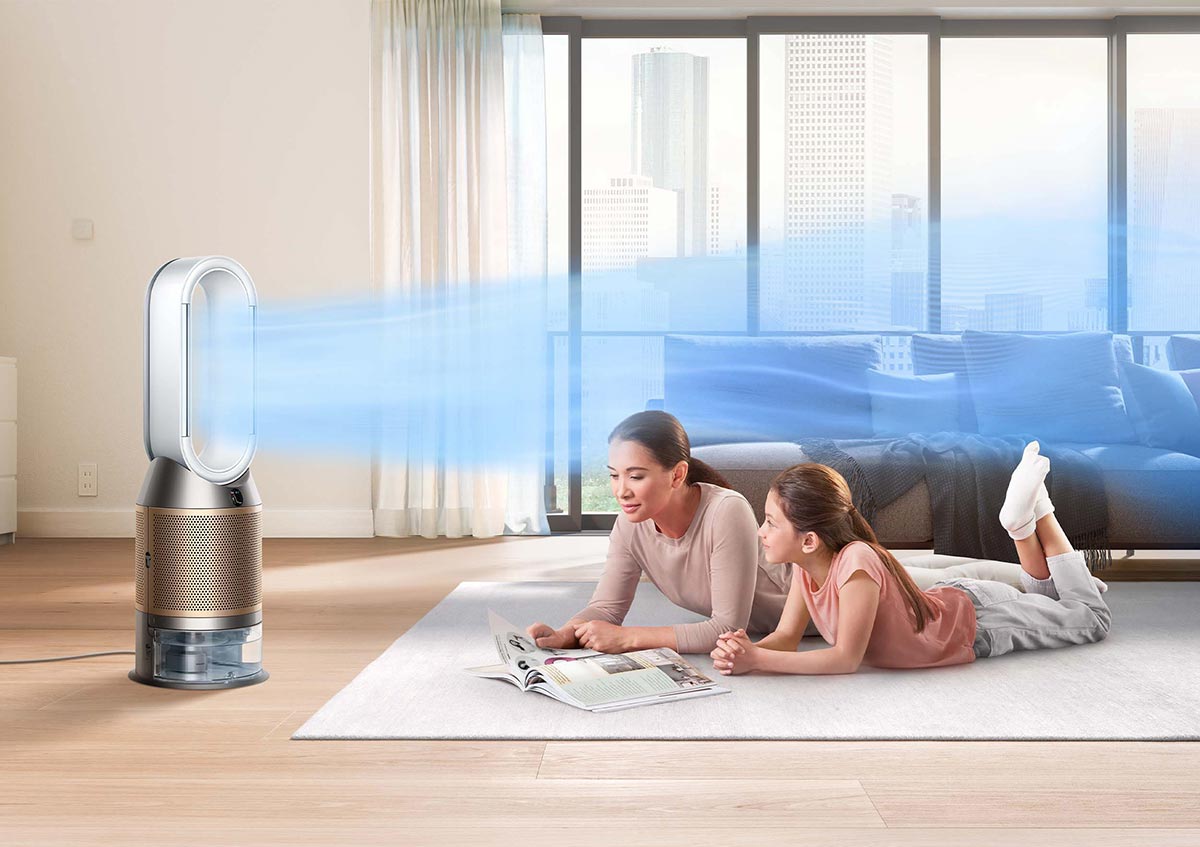 Eine Frau und ein Kind liegen auf einem Teppich vor einem Ventilator, der blaue Luft bläst.