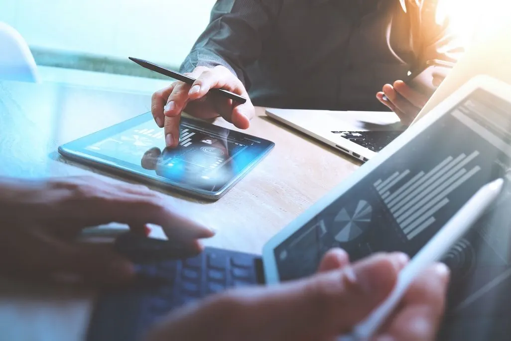 Personen arbeiten am Smartphone und Tablet mit Datenvisualisierung neben Laptop