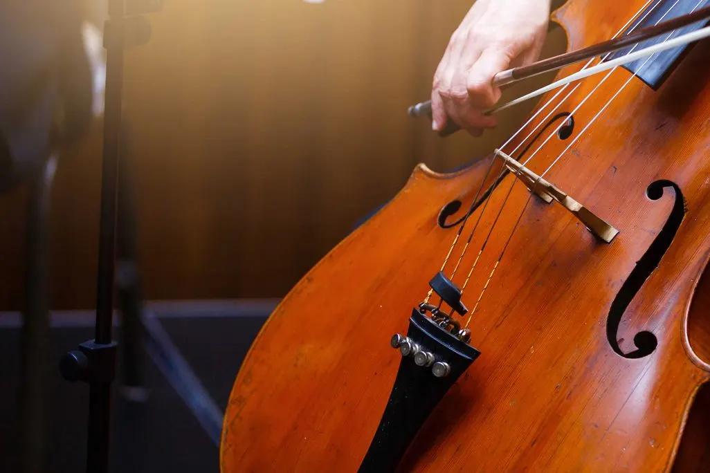 Eine Hand spielt ein Streichinstrument mit einem Bogen