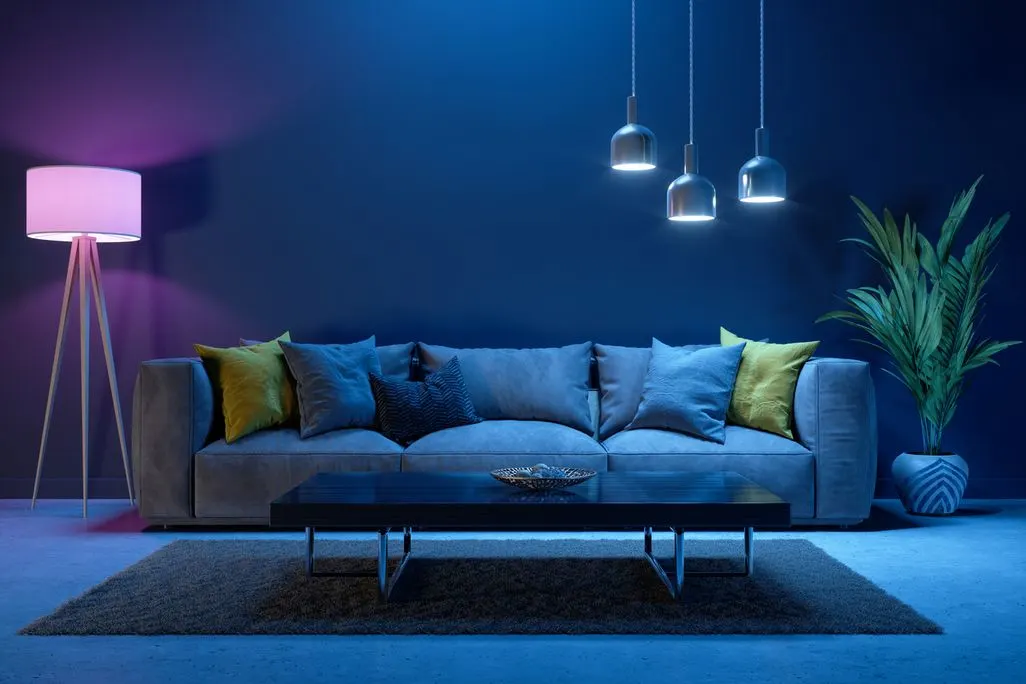 Modernes Wohnzimmer mit bunter Beleuchtung und grauem Sofa.