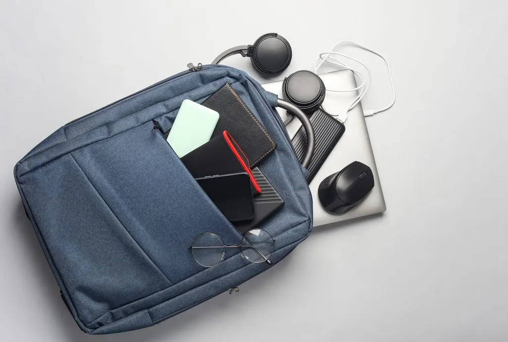 Geöffnete blaue Laptoptasche mit Notebook, Kopfhörern und Zubehör.