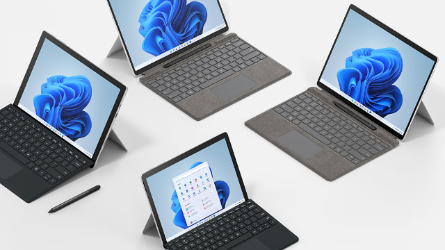 Mehrere Tablets mit Tastaturen stehen auf einem weißen Tisch, einige zeigen ein blaues Blumenmuster, eines einen Kalender.