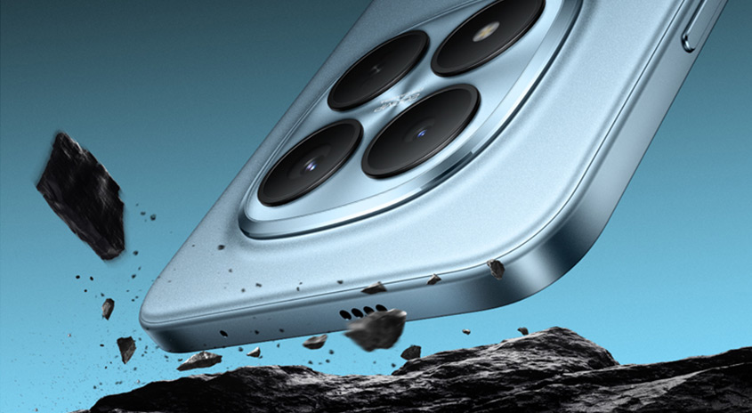  Schräg von unten gezeigte Smartphone-Rückseite in Hellblau mit großem Vierfach-Kameramodul, das dynamisch über einer Felslandschaft schwebt, während Gesteinsbrocken in der Luft auseinanderfliegen.