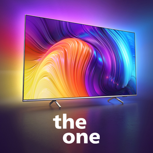 Ein Flachbildfernseher steht auf einem Tisch. Der Bildschirm zeigt ein abstraktes, farbenfrohes Muster. Darunter steht der Text "the one".