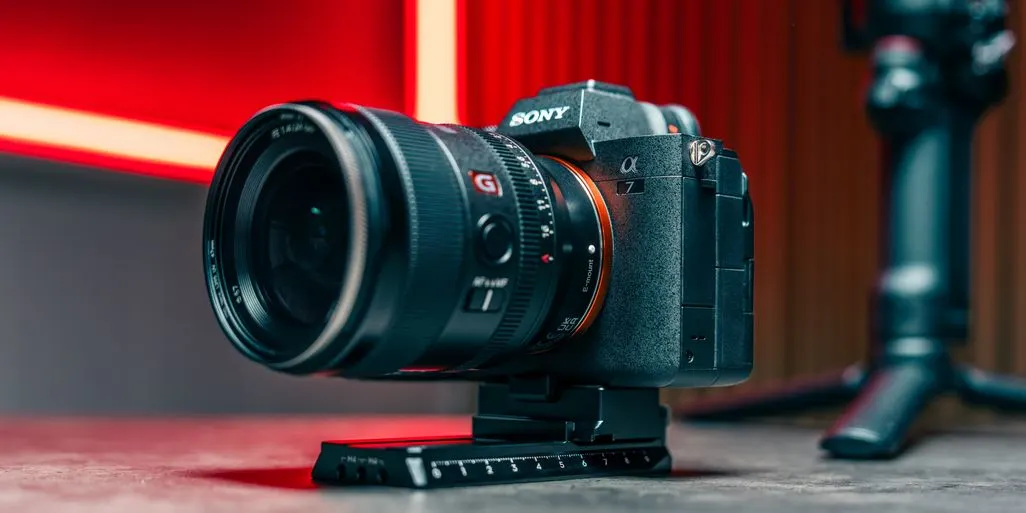 Sony Kamera mit Objektiv steht auf einem Tisch vor rotem Hintergrund