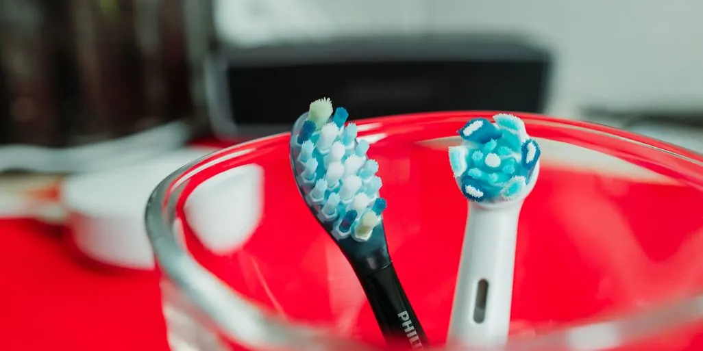 Elektrische Zahnbuerstenkoepfe von Philips und Oral B vor einem Glas