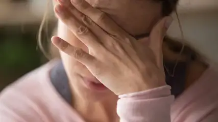 Frau greift sich mit Hand auf die Stirn