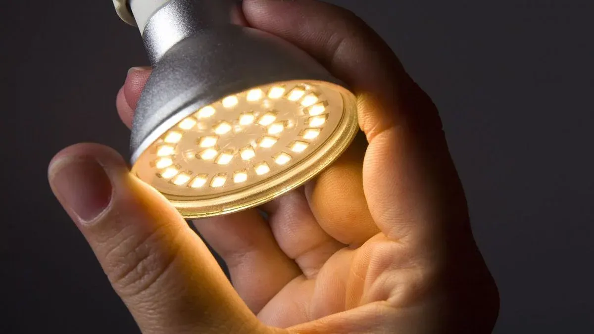 Hand hält LED eingeschaltete Lampe.