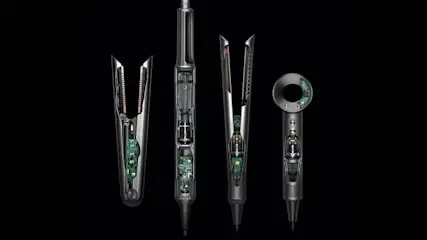 Vier Dyson-Styler und -Heißluftfön-Modelle in Schwarz und Silber mit sichtbarer Elektronik und internen Komponenten auf schwarzem Hintergrund – darunter zwei Lockenstäbe mit Gleitaufsätzen, ein vertikaler Heißluftfön und ein kompaktes Handgerät mit digitalem Display.